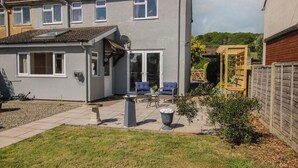 Een woonhuis met een terras, zitplaatsen buiten en een tuin.