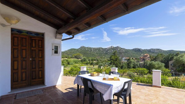A patio with a table set for dining, overlooking a mountainous landscape.