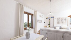 A modern kitchen with a dining area, a large window, and a pendant light.