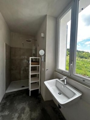 A bathroom with a shower, a sink, a window, and a view of greenery. - La Torre Granaia (EUROPE)