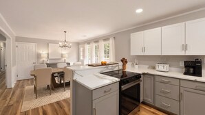 Una cucina moderna con mobili bianchi, un piano cottura nero e una macchina per il caffè.