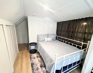 Une chambre à coucher avec un lit, une table de chevet et une fenêtre avec des rideaux.