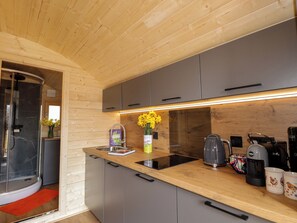Una cocina moderna con armarios grises, encimera de madera, estufa integrada y cafetera.