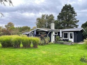Ein zweistöckiges Haus mit Schornstein, einer Veranda und einem gepflegten Rasen.
