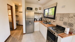 Cocina compacta con refrigerador, microondas, estufa y lavamanos.