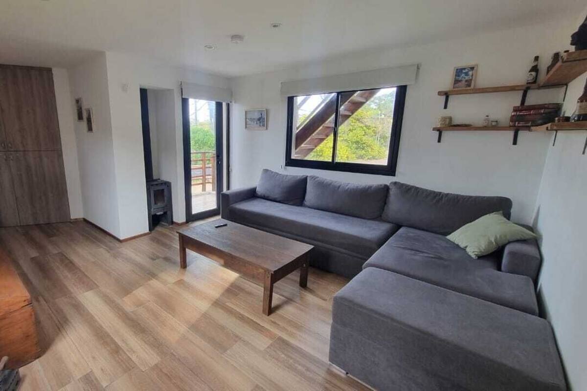 Una sala de estar moderna con un sofá, una mesa de centro y un ventanal corredero que da a un balcón.