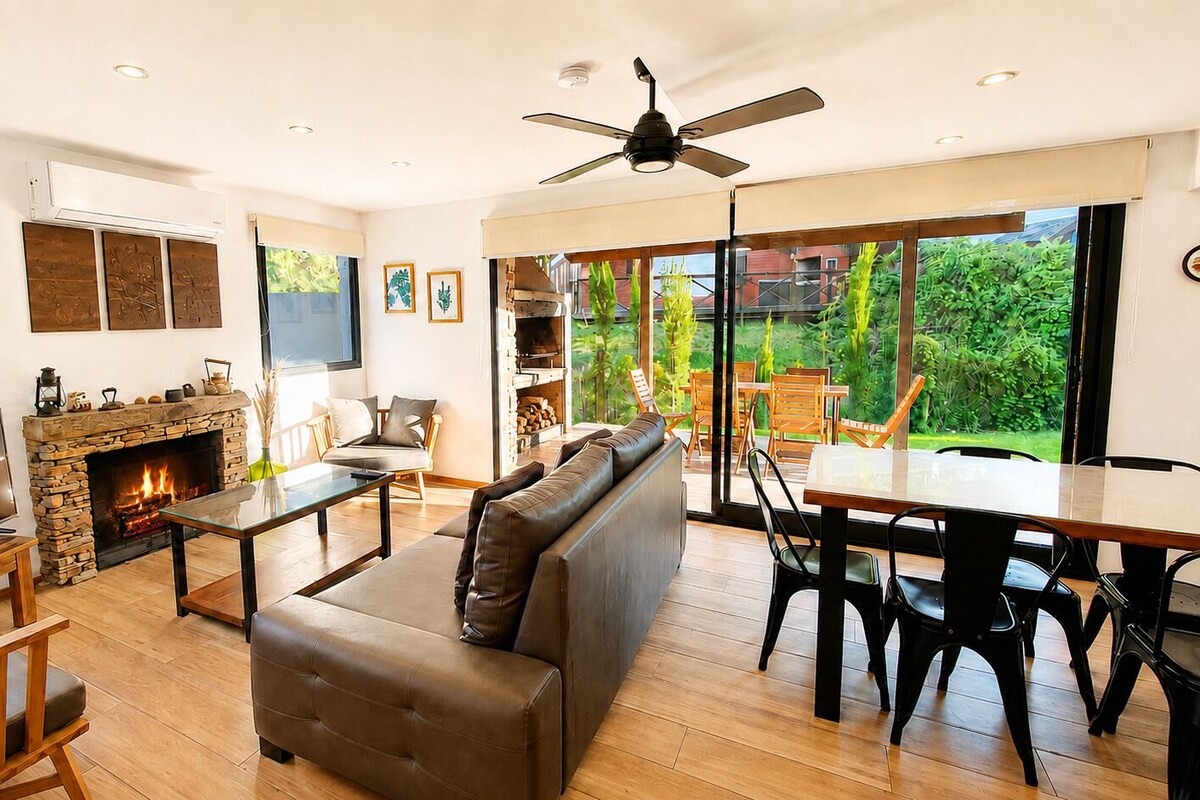 Una sala de estar moderna con chimenea, un sofá, una mesa de comedor y un televisor.