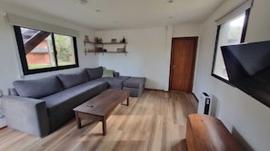 A living room with a sectional sofa, a wooden coffee table, and a flat-screen TV mounted on the wall. - Complejo Playa Bonita Mar Azul 100m playa (Mar Azul)