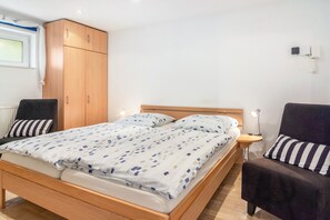 A bedroom with a wooden bed, two bedside tables, a wardrobe, and a chair. - Koch Apartment – Quiet Souterrain up to 80 m², Near Bad Grund & Osterode, Sleeps 6 (Bad Grund)