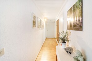 A hallway with framed pictures on the walls, a wooden floor, and a white reception desk with a vase of flowers. - Koch Apartment – Quiet Souterrain up to 80 m², Near Bad Grund & Osterode, Sleeps 6 (Bad Grund)
