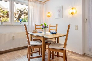 Ein Essbereich mit einem Holztisch, Stühlen, einer Blumenvase und Wandleuchten.