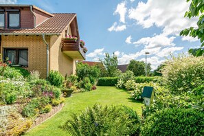 A residential house with a garden, a balcony with flowers, and a birdhouse. - Koch Apartment – Quiet Souterrain up to 80 m², Near Bad Grund & Osterode, Sleeps 6 (Bad Grund)