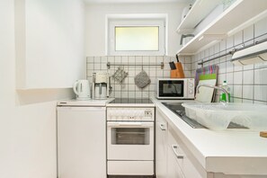 Eine kompakte Küche mit Einbauofen, Mikrowelle und einem kleinen Fenster über der Spüle.