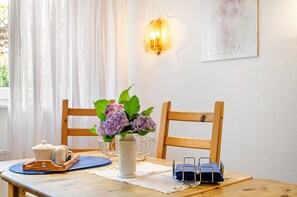 A dining table with a vase of flowers, a teapot, and a blue placemat. - Koch Apartment – Quiet Souterrain up to 80 m², Near Bad Grund & Osterode, Sleeps 6 (Bad Grund)