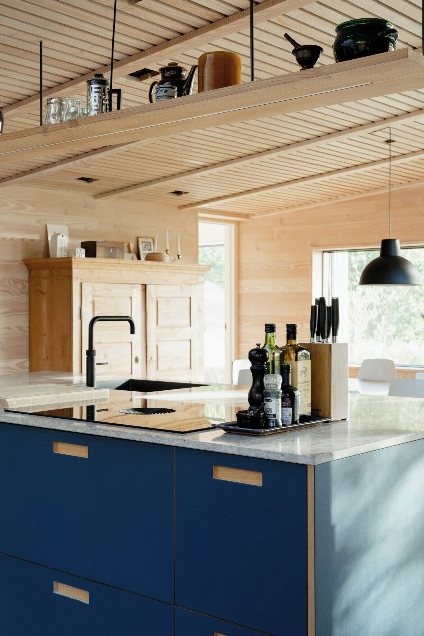 A modern kitchen with wooden cabinetry, a central island, and a hanging pendant light.