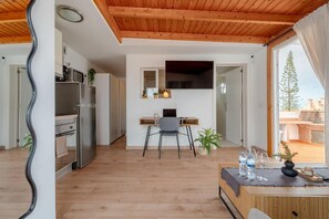 A modern kitchen with a refrigerator, microwave, and wooden cabinets. There is a dining area with a table, chairs, and a view of the outdoors. - Vacation Apartment 'Ático Con Barbacoa Y Terraza' with Sea View, Private Terrace and Wi-Fi (Fañabé)