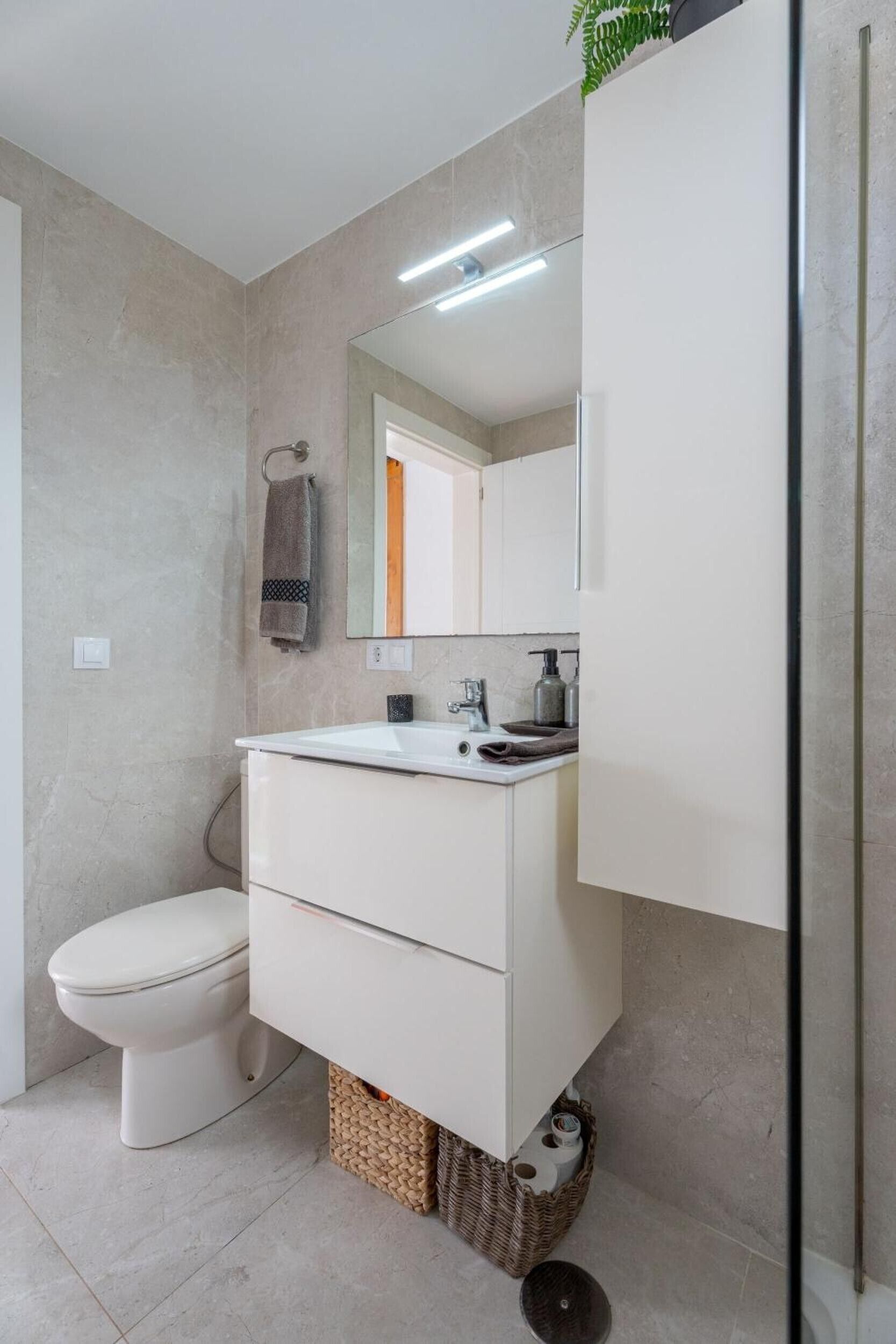 Een moderne badkamer met toilet, wastafel en spiegel.
