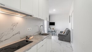 A modern kitchen with a built-in stove, white cabinets, and a marble backsplash. - Vacation Apartment 'Balcón Panorámico, Mar Y Puesta Sol' with Sea View, Balcony and Wi-Fi (Guargacho)