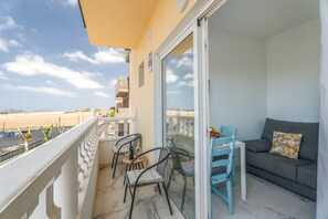 Een balkon met uitzicht op het strand, een bank en twee stoelen.