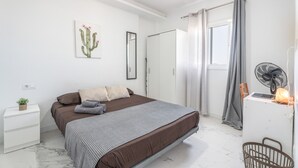 A bedroom with a bed, bedside table, curtains, a fan, and a window. - Vacation Apartment 'Balcón Panorámico, Mar Y Puesta Sol' with Sea View, Balcony and Wi-Fi (Guargacho)