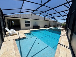 A swimming pool with a sunken hot tub, lounge chairs, and a covered patio area. - 	Walk to Brownwood Square, Bars/Food/Music/Shopping POOL/SPA Golf cart included! (The Villages)