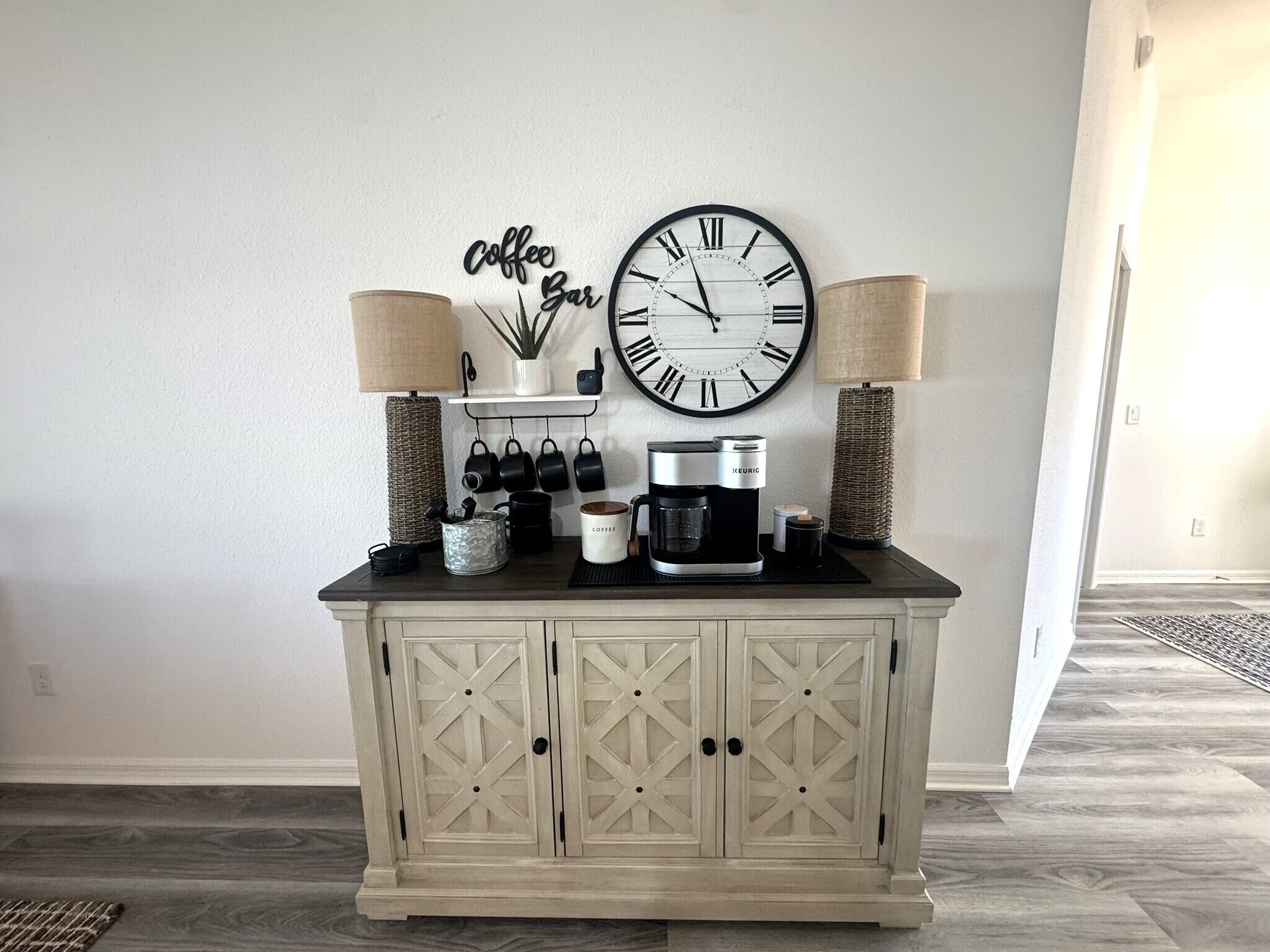 A kitchen area with a coffee station, a wall clock, and a cabinet with drawers.