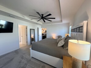 A bedroom with a bed, a ceiling fan, a TV, and a lamp. - 	Walk to Brownwood Square, Bars/Food/Music/Shopping POOL/SPA Golf cart included! (The Villages)