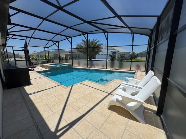 Una piscina exterior cubierta con un jacuzzi, sillas de descanso y una zona de terraza.