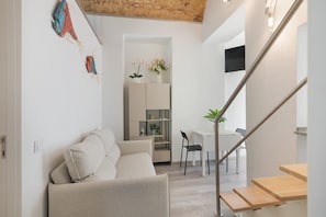 Un intérieur moderne comprenant un canapé, une table à manger, des chaises, un escalier et une plante.