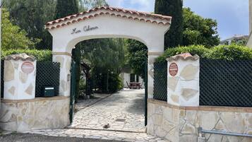 A stone archway with 'Mon Cabanon' signage, leading to a paved pathway.