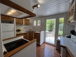 Eine Küche mit Holzschränken, einer eingebauten Mikrowelle, einem Spülbecken und einem Fenster mit Blick auf einen Garten.