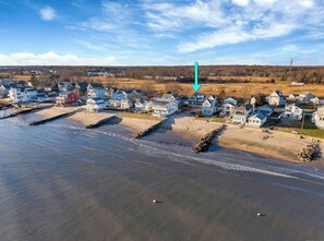 An aerial view of a coastal residential area with houses, a beach, and a body of water. - Luxury Coastal Retreat w/ Private Beach Access + Water Views, Clinton, CT (Clinton)