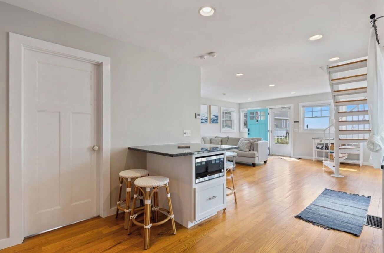 A spacious kitchen with a central island, wooden flooring, and a staircase leading to an upper level.