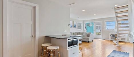 A spacious kitchen with a central island, wooden flooring, and a staircase leading to an upper level.