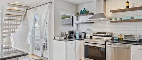 A modern kitchen with white cabinets, a built-in oven, a dishwasher, and a stove.