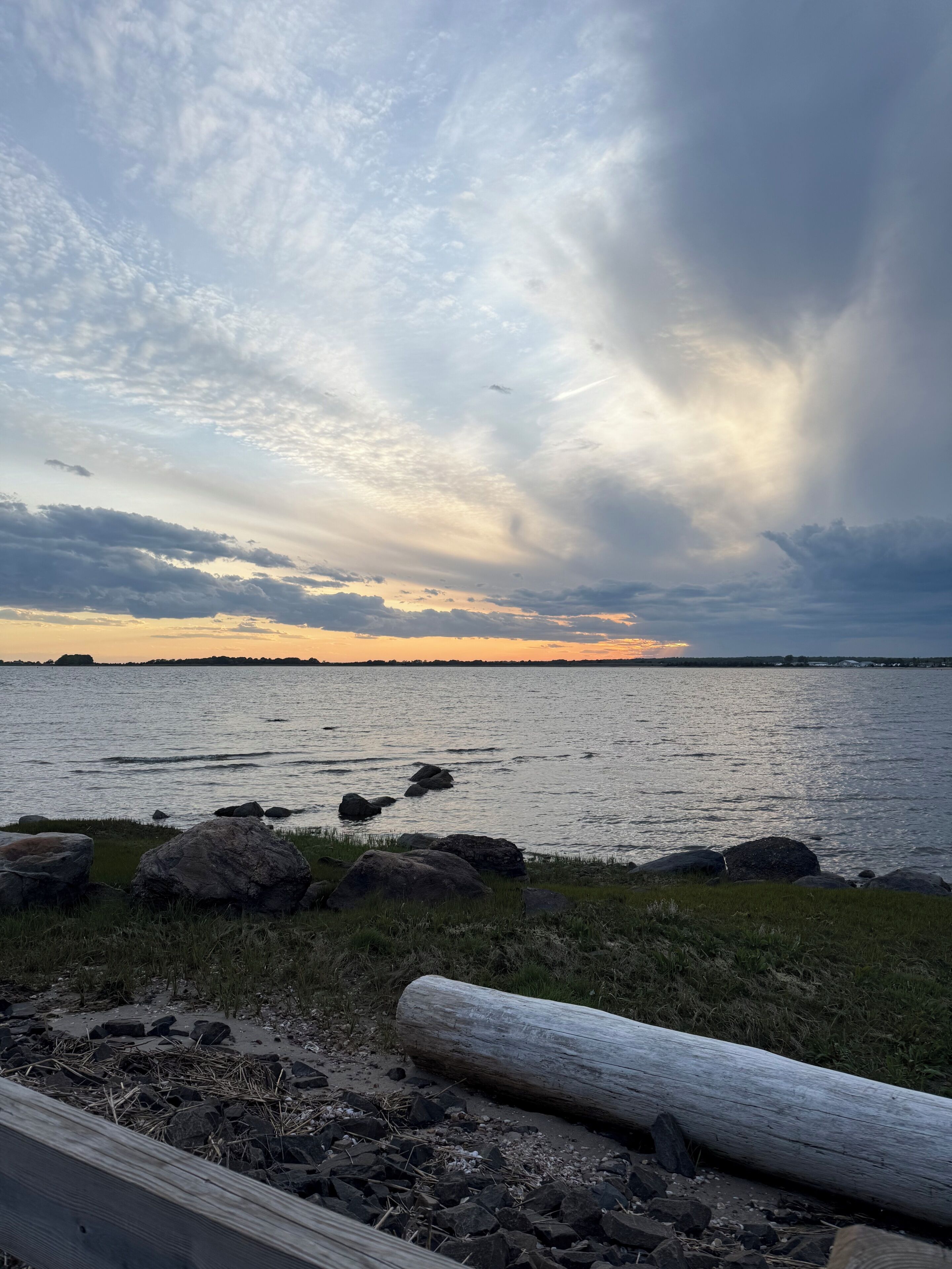 A coastal landscape with a body of water, rocks, and a wooden log.