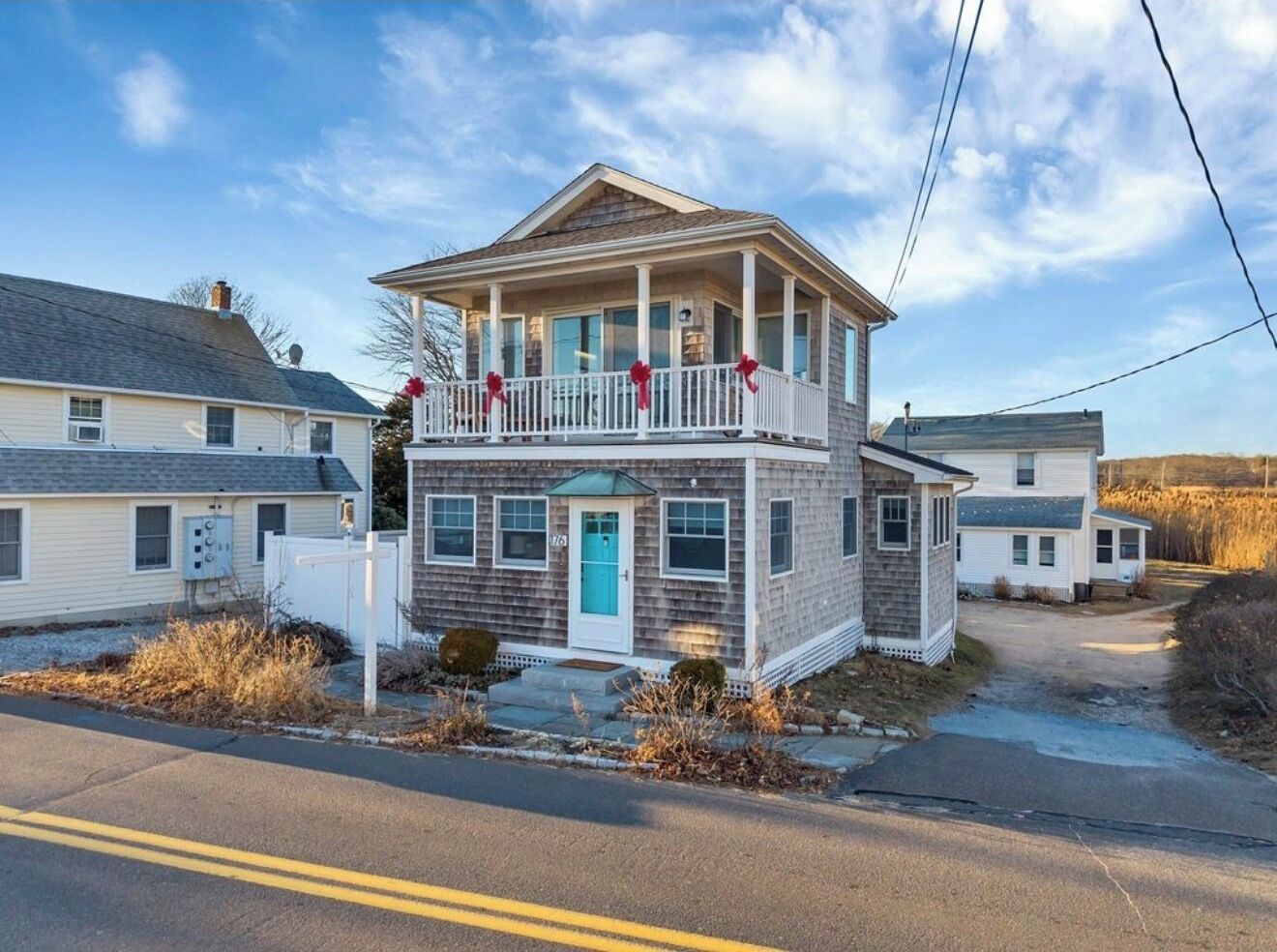 Une maison à deux étages avec un balcon, une véranda à l’avant et un garage.