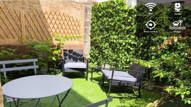 A patio with a table and chairs, a wooden lattice wall, and a vertical garden.