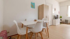 A dining area with a white table and chairs, a small plant, and a radiator.