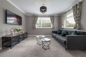 Ein Wohnzimmer mit Fernseher, Sofa, Couchtisch und einer Konsole mit Dekoration.