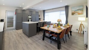 Una cucina moderna con mobili grigi, un'isola centrale e un'area pranzo con tavolo e sedie in legno.