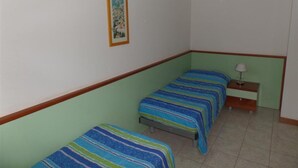 A room with two single beds, a nightstand with a lamp, and a framed picture on the wall. - Family Getaway With Communal Garden and Porch (San Michele al Tagliamento)