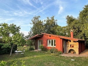 A small red brick house with a chimney, a garden with a table and chairs, and a clear blue sky. - 1927 house Rome's Appia Antica Park (Roma)