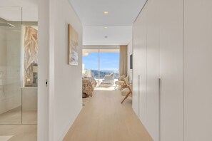 Ein moderner Hotelkorridor mit einem Bett, einer Sitzecke und Blick zum Himmel.