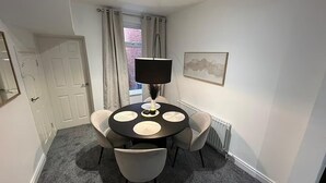 A small, round dining table with four chairs, a black lamp, and a framed picture on the wall.