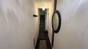 A narrow hallway with a staircase leading to a landing.