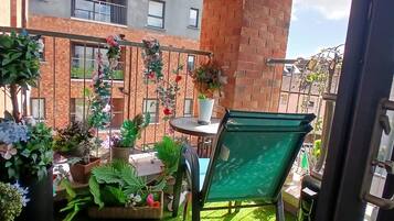 A balcony with various potted plants and a chair.