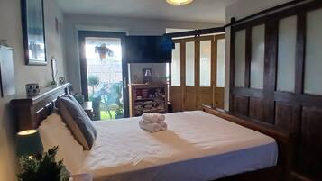 A bedroom with a bed, a nightstand, a bookshelf, and a window.