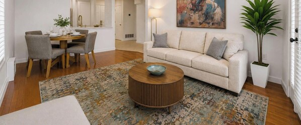Ein Wohnzimmer mit Sofa, Couchtisch und Essbereich mit Stühlen.