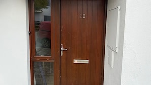 En moderne to-dørs indgang med en stenfassade, et nummereret dør og en dørmåtte.